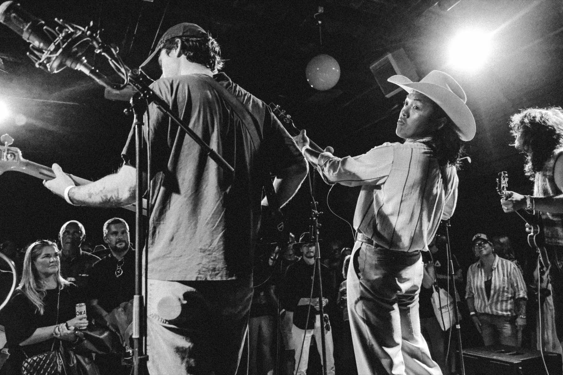 Johnny Devils on stage, the singer in a cowboy hat looking back over his shoulder at the crowd, black and white