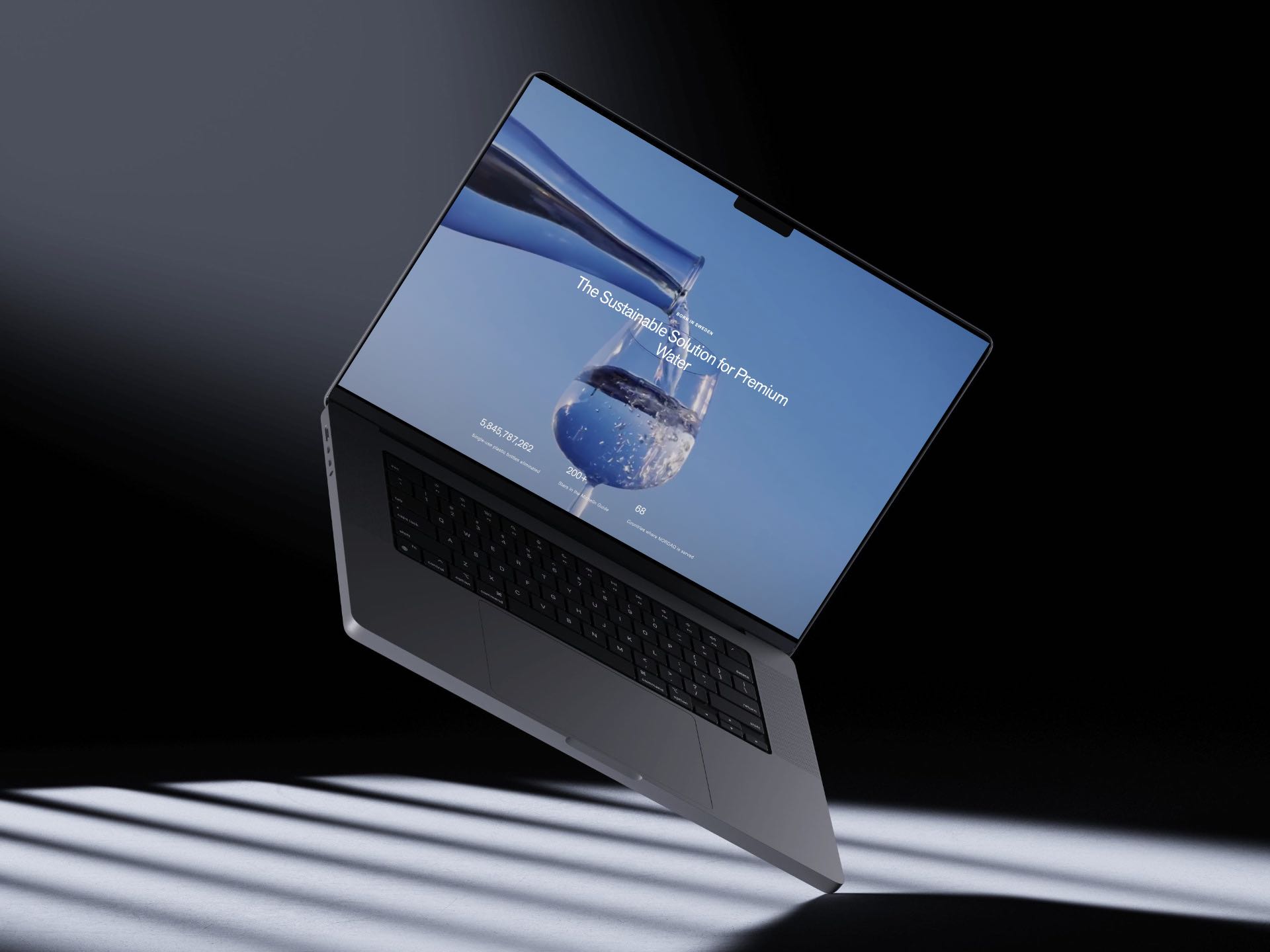 Nordaq home page on a floating MacBook: a bottle pouring, the headline Sustainable Solution for Premium Water