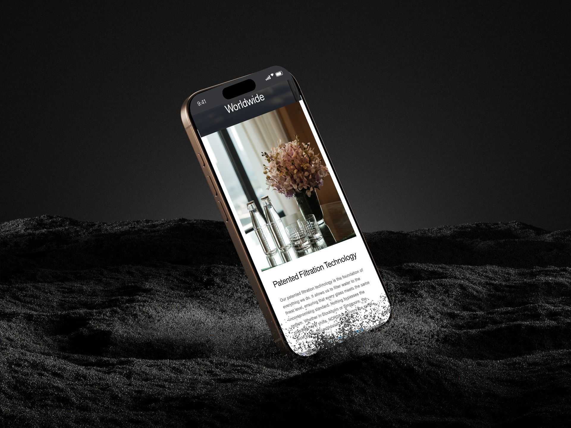The Nordaq Technology page on an iPhone in dark sand, two bottles and orchids above Patented Filtration Technology