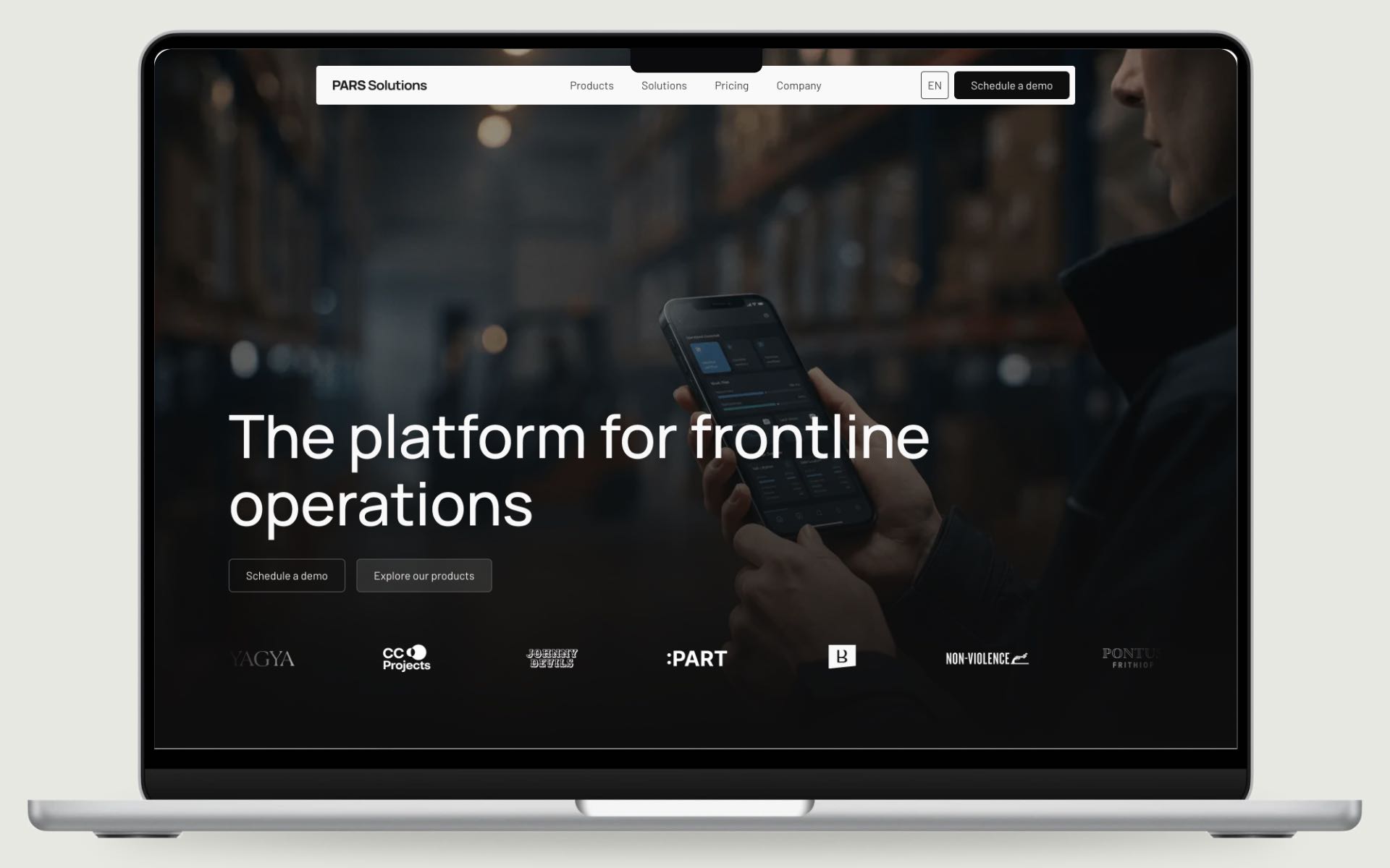 The new PARS home page on a MacBook: The platform for frontline operations, over a warehouse photo with a phone in hand