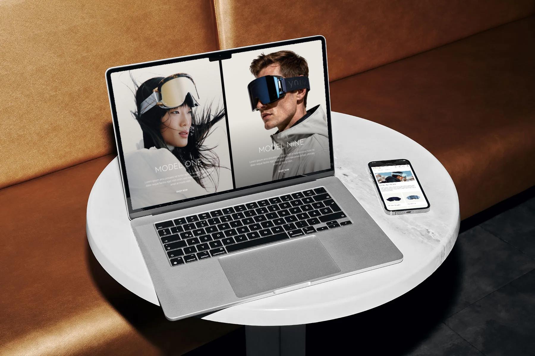 YNIQ on a MacBook and iPhone on a white marble cafe table: Model One and Nine on the laptop, the collection page on the phone